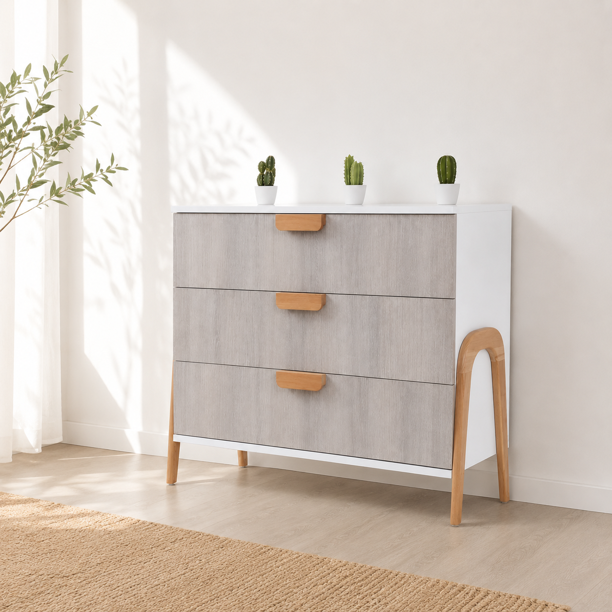 Commode scandinave gris clair et blanc à 3 tiroirs intégrée dans un décor minimaliste lumineux avec pieds en bois naturel.
