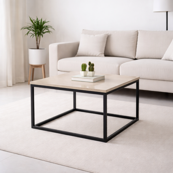 Table basse carrée moderne avec plateau effet pierre beige et structure en métal noir, intégrée dans un salon minimaliste lumineux.