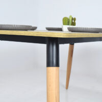 Table à manger scandinave moderne avec plateau en bois clair et pieds en bois naturel et métal noir, intégrée dans un décor intérieur simple et lumineux.