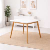 Table carrée blanche avec pieds en bois naturel, intégrée dans un décor minimaliste sans chaises, style scandinave moderne.