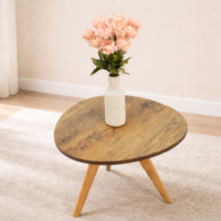 Table basse ovale en bois naturel avec pieds inclinés, décorée d’un vase blanc et de fleurs, intégrée dans un salon aux murs clairs et au style moderne.