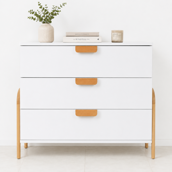 Commode blanche moderne à 3 tiroirs avec poignées et pieds en bois naturel dans un décor minimaliste.