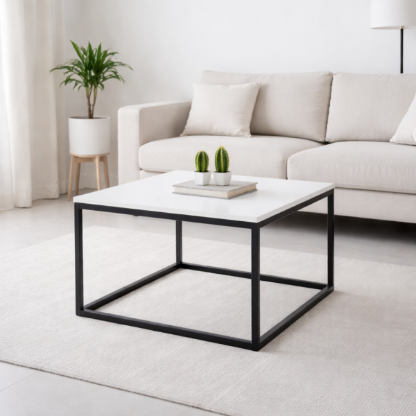 Table basse carrée moderne avec plateau blanc et structure métallique noire, intégrée dans un salon minimaliste et lumineux.