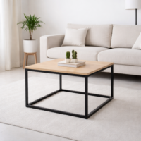 Table basse carrée moderne avec plateau en bois clair et structure en métal noir, intégrée dans un salon minimaliste lumineux.