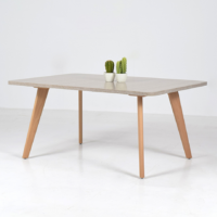 Table basse carrée en bois clair avec pieds en bois naturel, photographiée sur fond blanc avec vase décoratif.