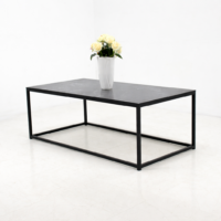 Table basse rectangulaire en métal noir avec plateau foncé, présentée sur fond blanc avec un vase décoratif, style moderne et minimaliste.