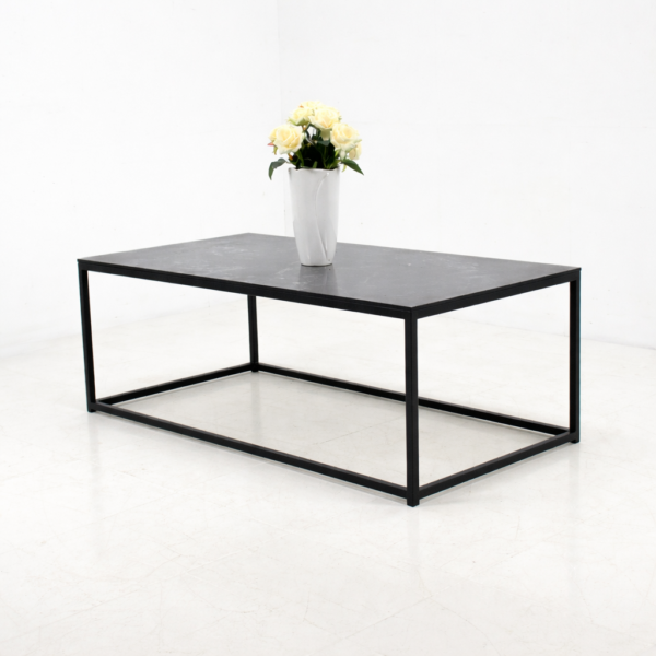 Table basse rectangulaire en métal noir avec plateau foncé, présentée sur fond blanc avec un vase décoratif, style moderne et minimaliste.