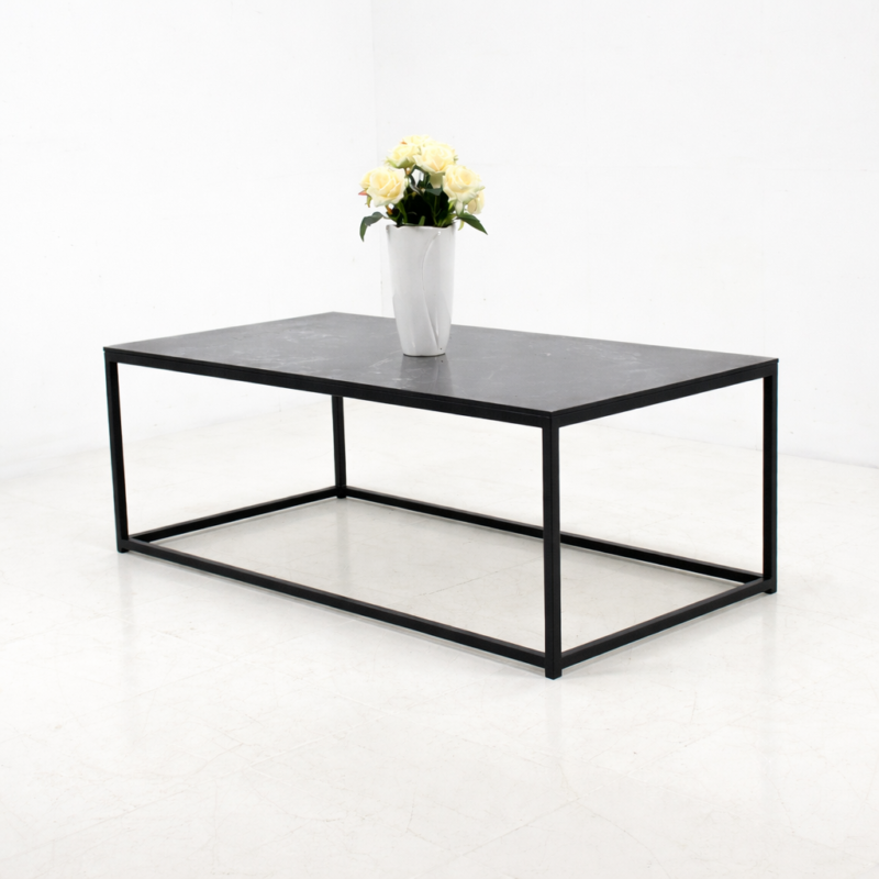 Table basse rectangulaire en métal noir avec plateau foncé, présentée sur fond blanc avec un vase décoratif, style moderne et minimaliste.