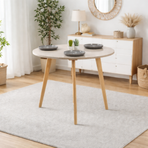 Table ronde scandinave en bois clair avec plateau beige, intégrée dans un décor intérieur minimaliste et lumineux, sans chaises.