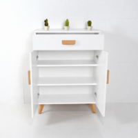 Meuble de rangement blanc moderne avec tiroir, portes et pieds en bois naturel sur fond blanc légèrement grisé.