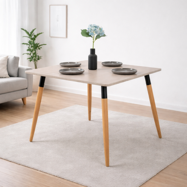 Table à manger moderne avec plateau clair et pieds en bois, décorée avec assiettes grises et vase floral, sur fond gris très clair – Tunisie