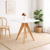 Table à manger scandinave blanche avec plateau carré et pieds en bois naturel, intégrée dans un décor intérieur simple, lumineux et moderne.