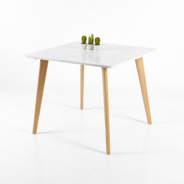 Table carrée blanche au design scandinave avec pieds en bois naturel, décorée de petites plantes, sur fond blanc épuré.