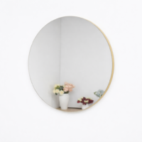 Miroir rond mural avec cadre fin doré installé sur un mur blanc, design moderne et minimaliste pour salon ou chambre.
