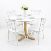 Ensemble salle à manger 5 pièces composé d'une table ronde plateau blanc avec pied en bois naturel et 4 chaises blanches style scandinave, décoré d'un bouquet de roses blanches