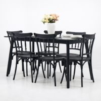 Salle à manger contemporaine avec table rectangulaire noire effet marbre et six chaises noires, décor minimaliste avec vase de fleurs sur la table.