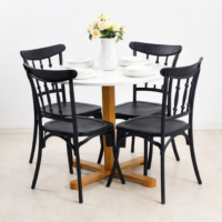 Table ronde blanche avec pied en bois et quatre chaises noires, décorée d’un vase de roses crème