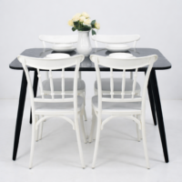 Table à manger noire effet marbre avec quatre chaises blanches dans une salle à manger moderne au mur beige et sol en bois clair