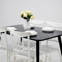 Table à manger noire effet marbre avec quatre chaises blanches dans une salle à manger moderne au mur beige et sol en bois clair
