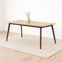 Table à manger en bois clair avec pieds foncés et vase décoratif sur tapis dans un décor minimaliste