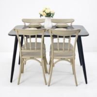 Table à manger moderne noire effet marbre avec quatre chaises beige et vase décoratif avec fleurs sur fond blanc