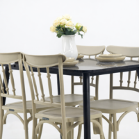 Table à manger moderne noire effet marbre avec quatre chaises beige et vase décoratif avec fleurs sur fond blanc