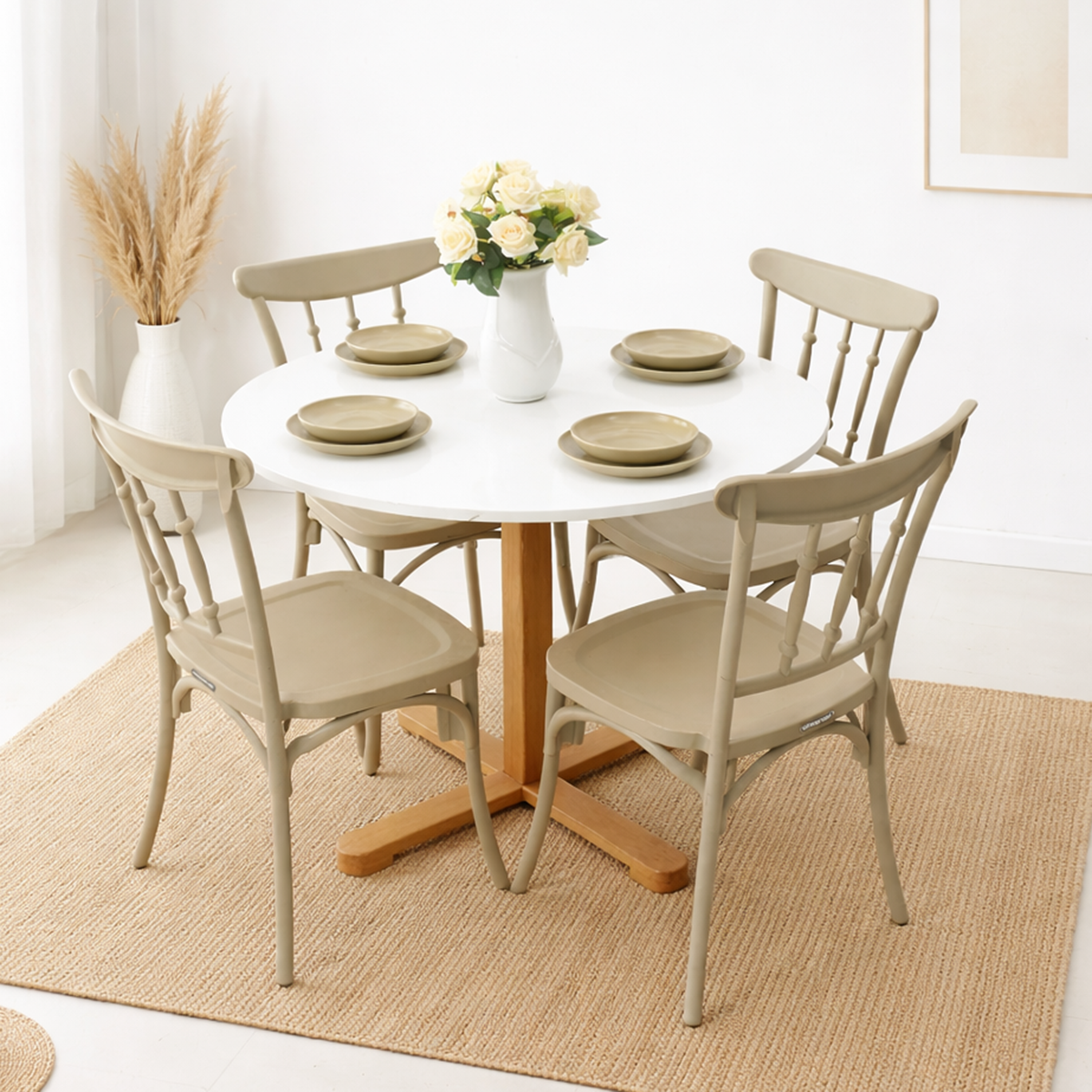 Table à manger ronde blanche avec quatre chaises beiges, posée sur un tapis en fibres naturelles dans un décor simple et lumineux avec vase décoratif