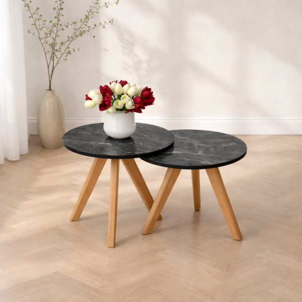 Deux tables basses gigognes rondes effet marbre noir avec pieds en bois dans un décor simple et lumineux