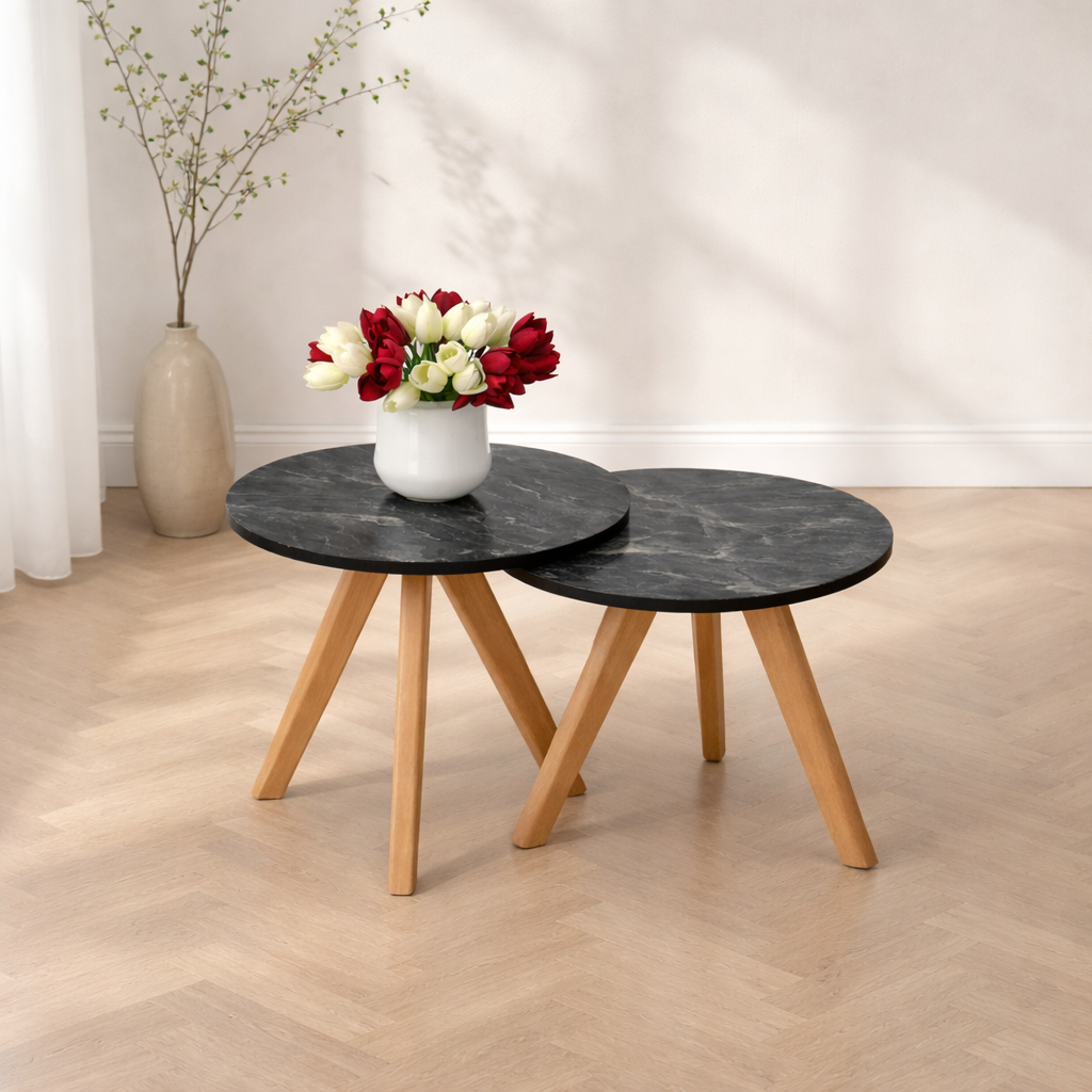Deux tables basses gigognes rondes effet marbre noir avec pieds en bois dans un décor simple et lumineux
