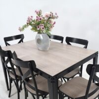 Ensemble salle à manger composé d'une table rectangulaire avec plateau effet bois clair et six chaises noires au design croisé, idéal pour une salle à manger moderne.