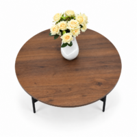 Table ronde en bois marron avec piètement métallique noir dans un intérieur moderne